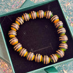 Round striped skateboard maple beads arranged in a circle in a green gift box.