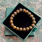 Yellow, green and black striped bead bracelet displayed in a green gift box.