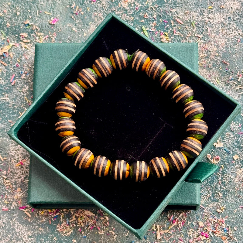 Yellow, green and black striped bead bracelet displayed in a green gift box.