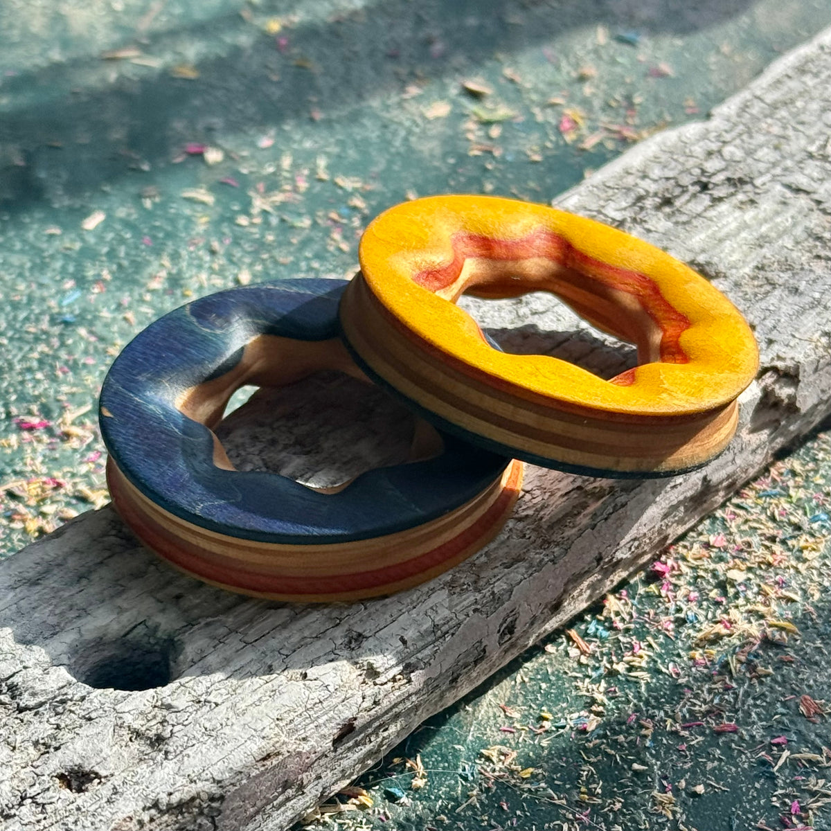 Reversible recycled skateboard wood ear tunnels on a weathered plank, handmade by Baltic Dew.