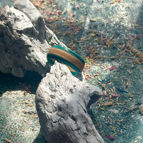 Blue recycled skateboard ring with layered maple and blue colour layers, displayed on weathered driftwood.