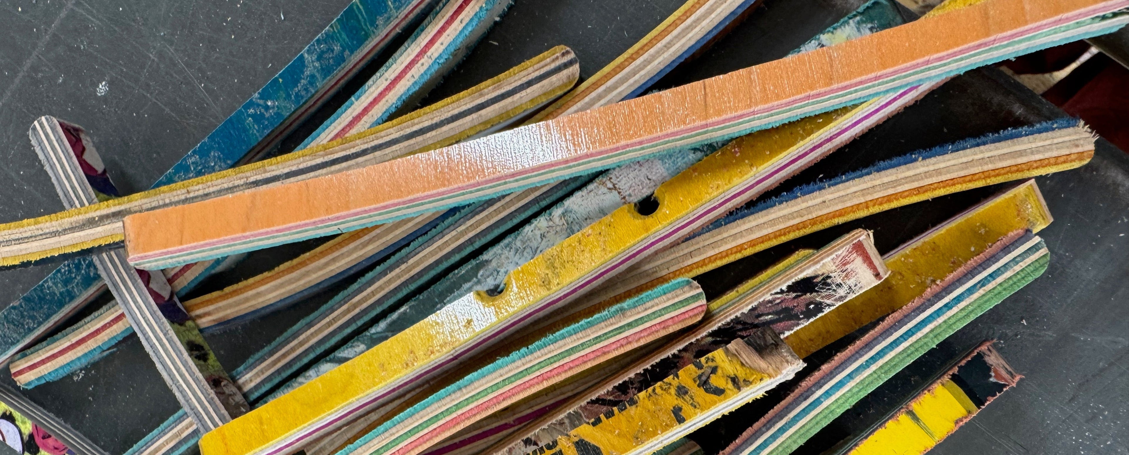 Stack of multicolored skateboard decks on a dark surface