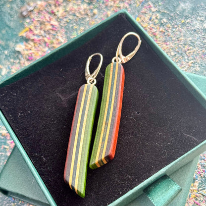 Colorful striped earrings in a green box with a multicolored background