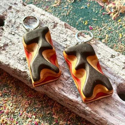 Wooden earrings with a wavy design on a wooden surface