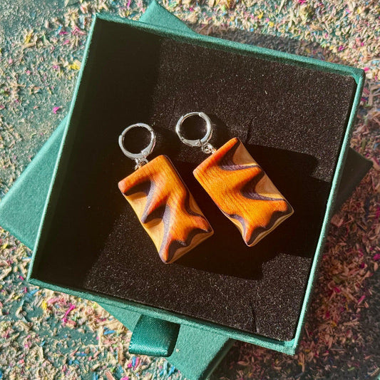 Pair of wooden earrings in a green box on a textured surface