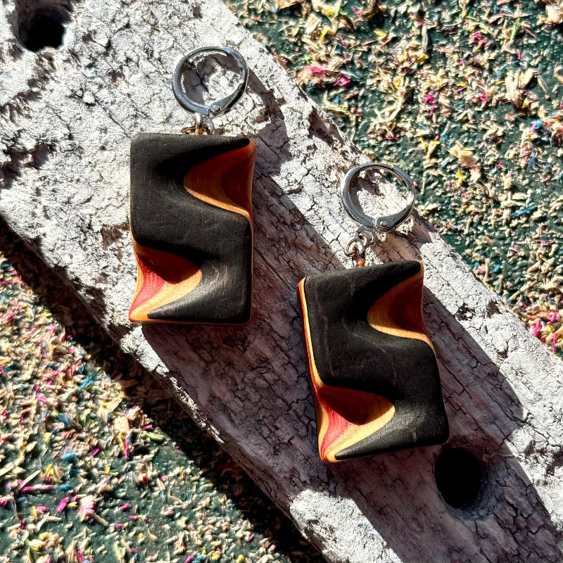 Black and orange earrings on a textured surface