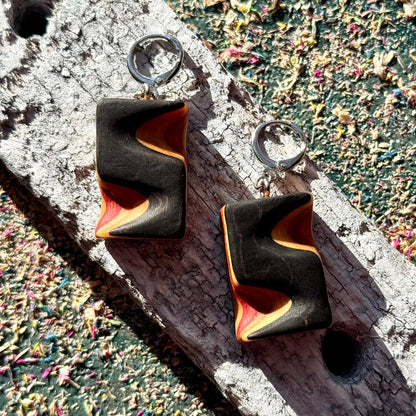 Black and orange earrings on a textured surface