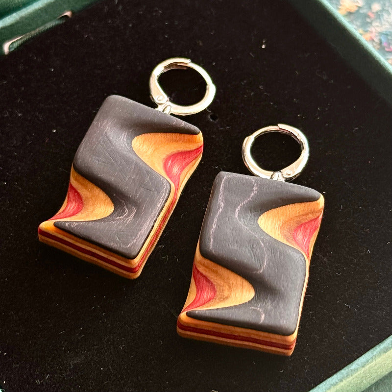 Pair of geometric wooden earrings on a dark surface