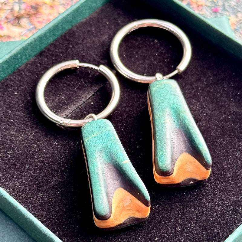 Teal and black lightweight wooden drop earrings with silver hoop fittings.