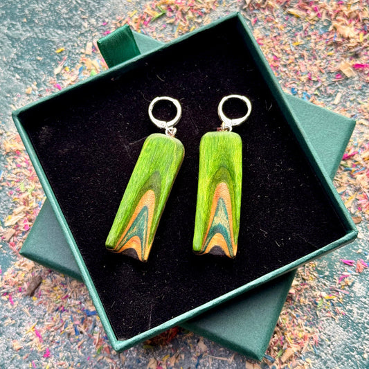 Green wooden earrings in a green box on a textured surface