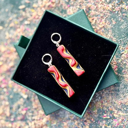 Colorful earrings in a green jewelry box on a glittery surface