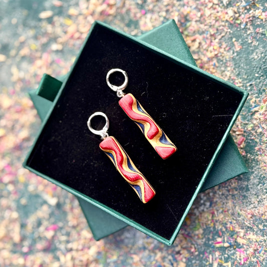 Colorful earrings in a green jewelry box on a glittery surface
