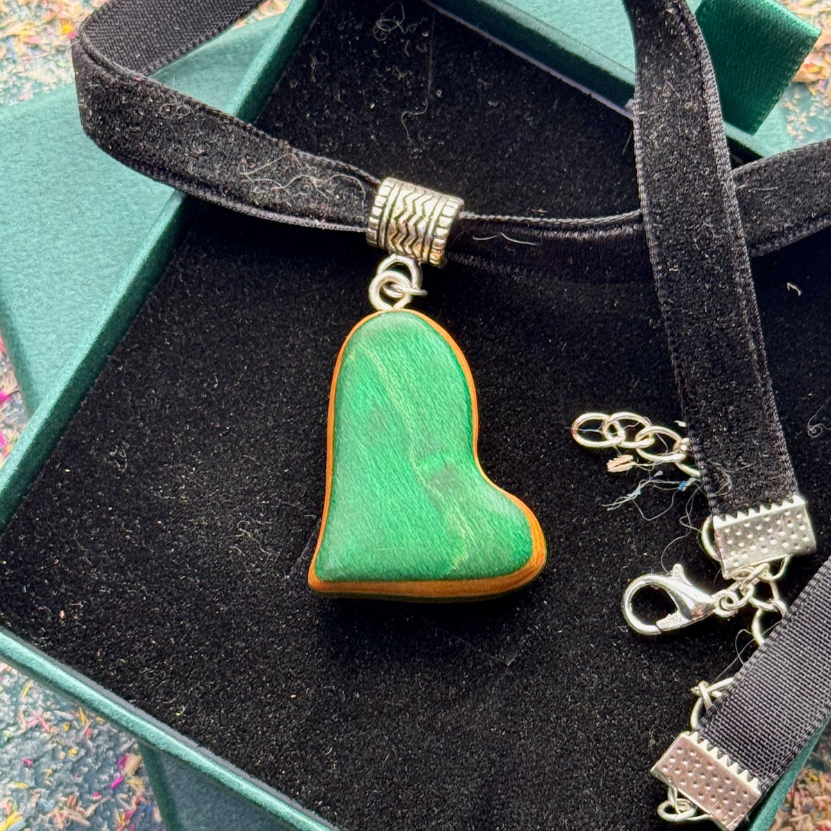 Reverse face of the reversible heart choker pendant, showing green skateboard maple with an orange edge.