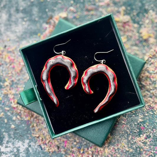 Heart-shaped earrings in a green box on a textured surface