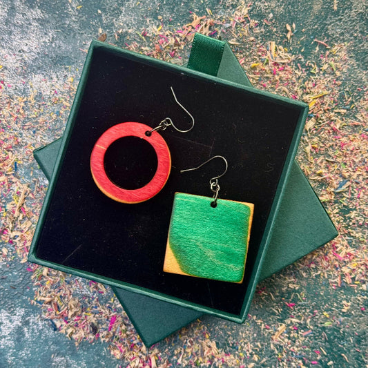 Wooden earrings in a green box on a textured surface