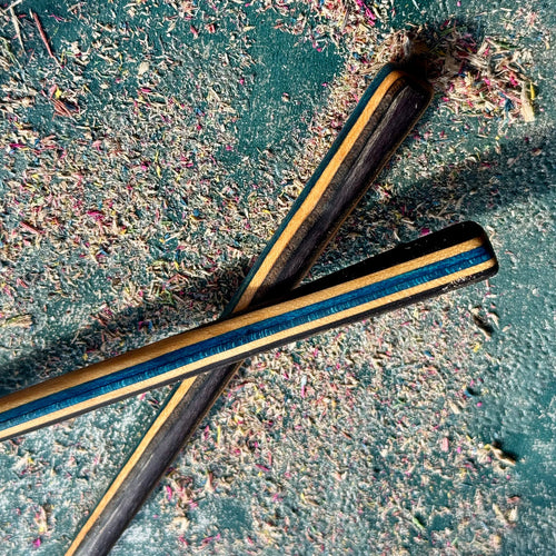 Blue Black Skateboard Hair Sticks made from layered recycled skateboard wood with visible wood shavings on surface