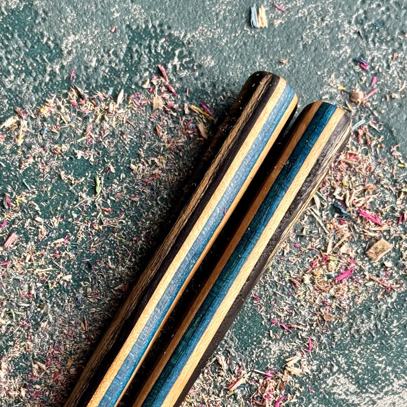 Close-up of two hair sticks in layered skateboard maple with blue and natural tones.