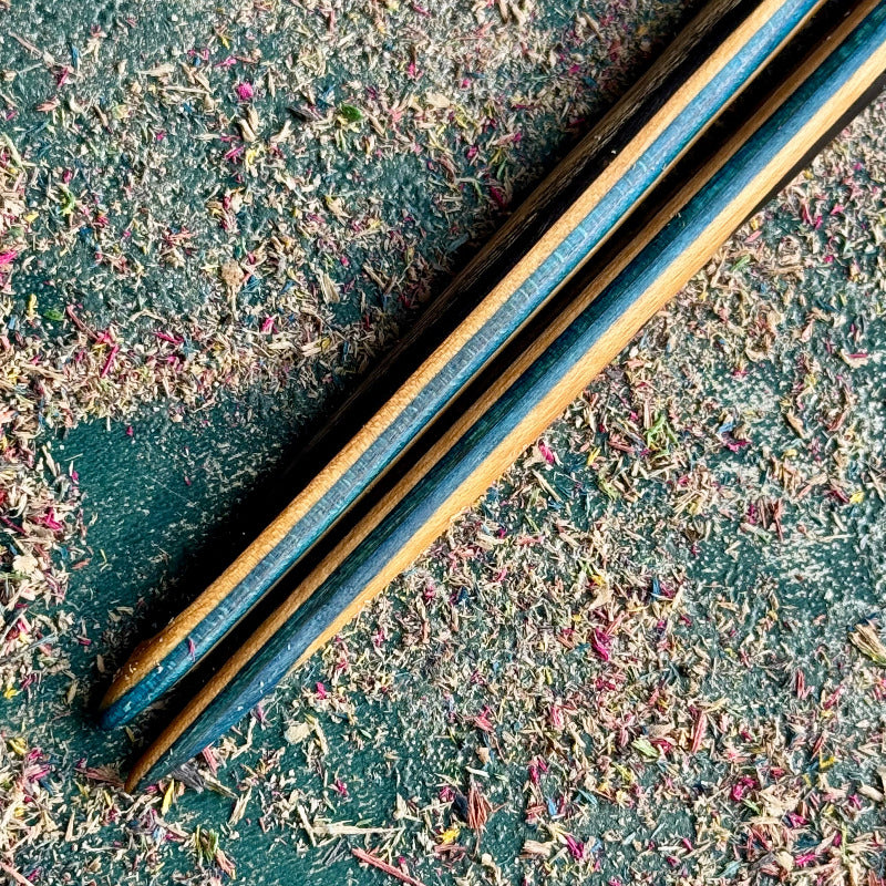 Blue Black Skateboard Hair Sticks made of layered recycled skateboard wood with blue and black stripes on textured surface
