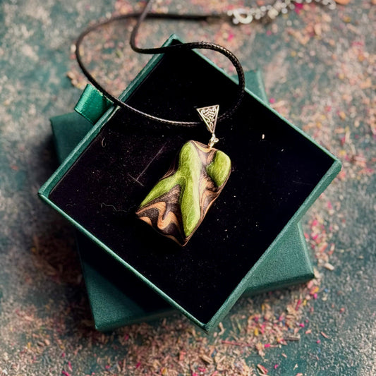 Green pendant necklace in a green box on a textured surface