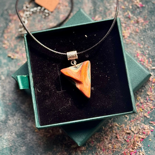 Necklace with a pendant in a green jewelry box on a textured surface
