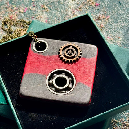 A black, pink and grey pendant made from recycled skateboard wood with oiled wooden finish, handmade by Baltic Dew