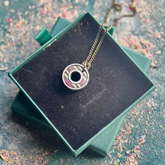 Necklace with a circular pendant on a black box with a textured surface