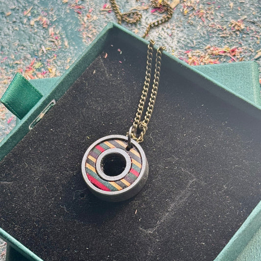 Necklace with a unique pendant in a green box on a textured surface