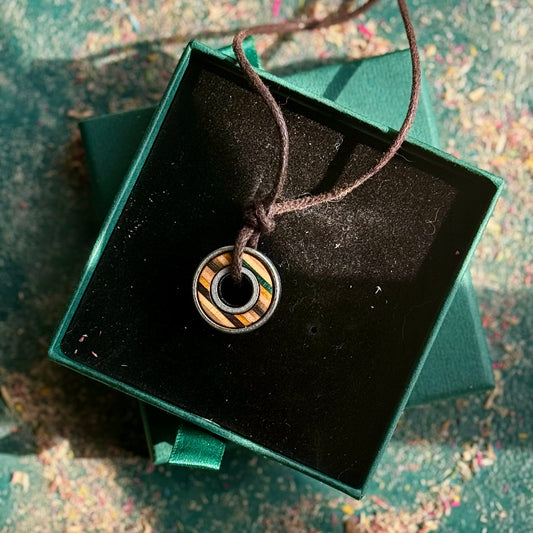 Necklace with a circular pendant in a green box on a textured surface