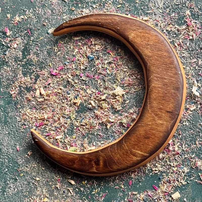 Crescent moon hair fork in recycled skateboard maple, shown flat with warm brown grain and a pale edge line.
