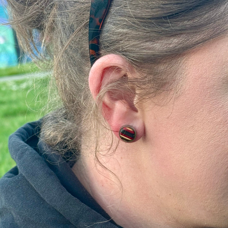 Small round wooden stud earring shown on the ear for scale.