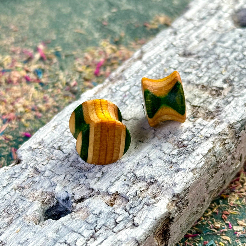 handmade wooden plugs with green and natural colour tones displayed on textured wood surface