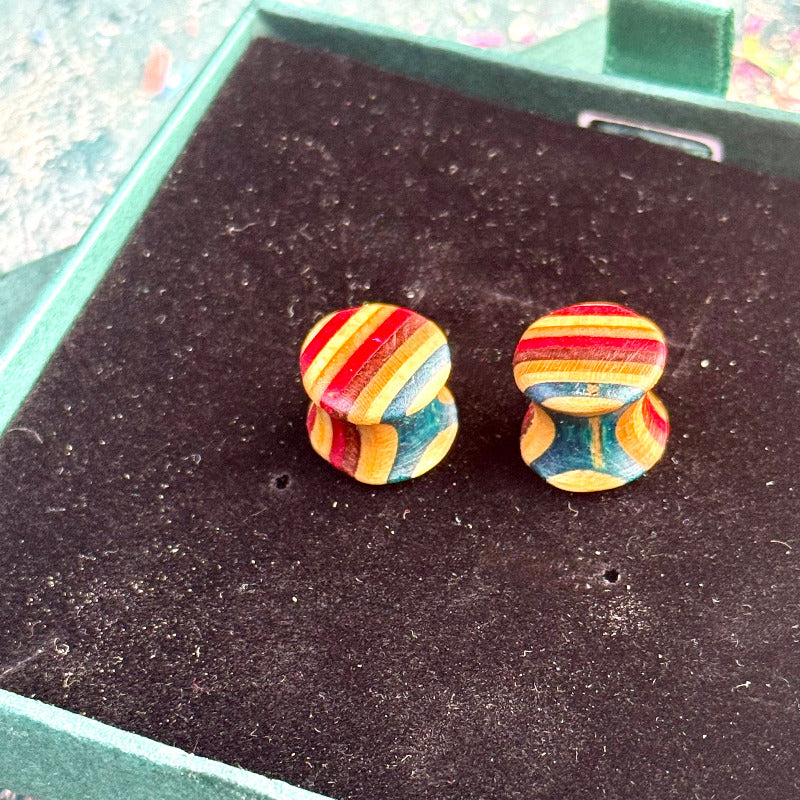 Hand-carved skateboard wood plugs in teal, red and blue colour tones displayed in a green gift box.