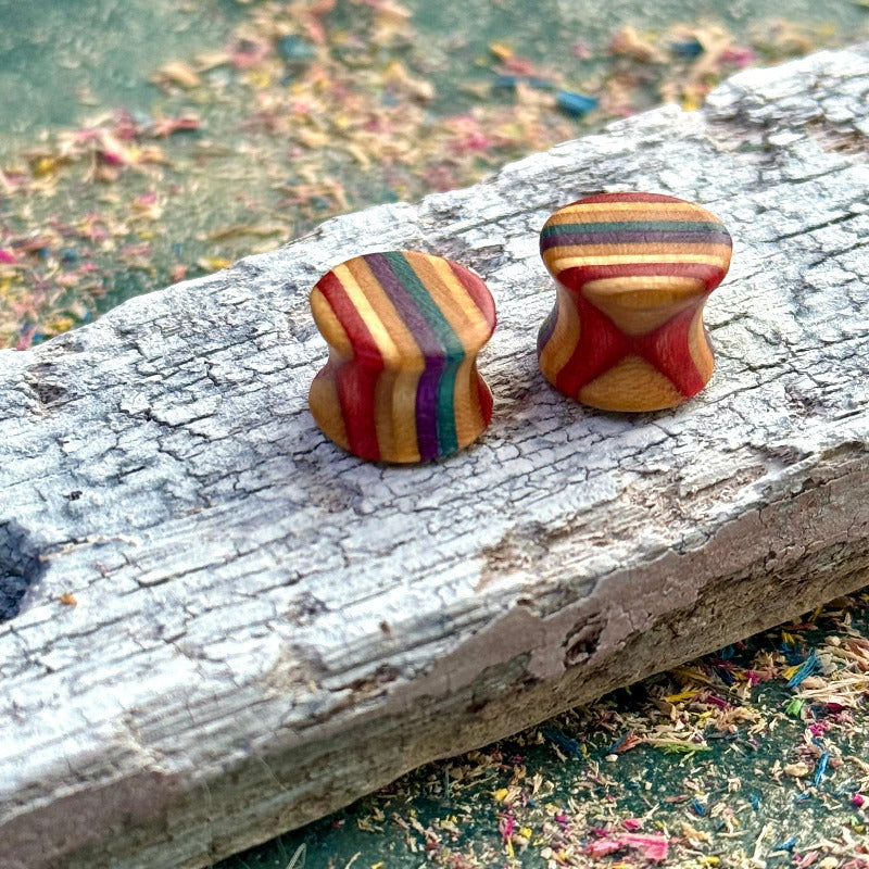 Recycled skateboard wood plugs with curved shape and mixed colour tones on a textured wooden surface.