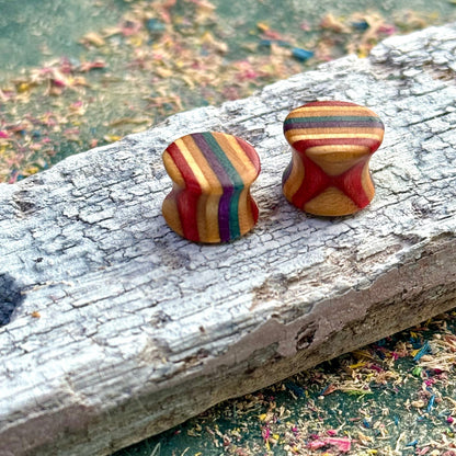 Recycled skateboard wood plugs with curved shape and mixed colour tones on a textured wooden surface.