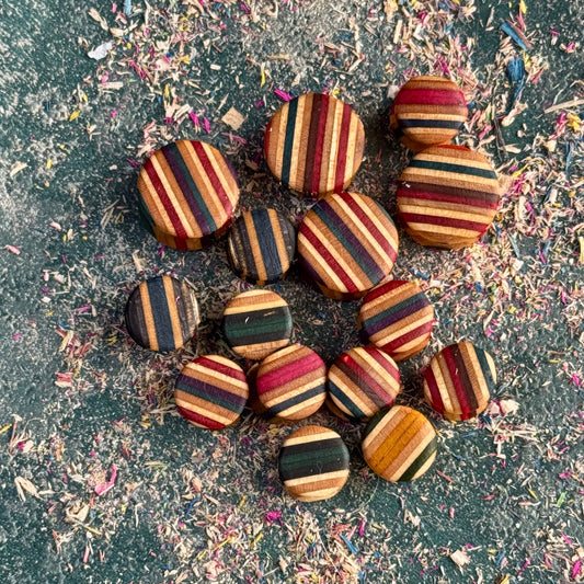 Custom Double Flare Ear Plugs and Tunnels made from colorful recycled skateboards with striped wood patterns on textured surface