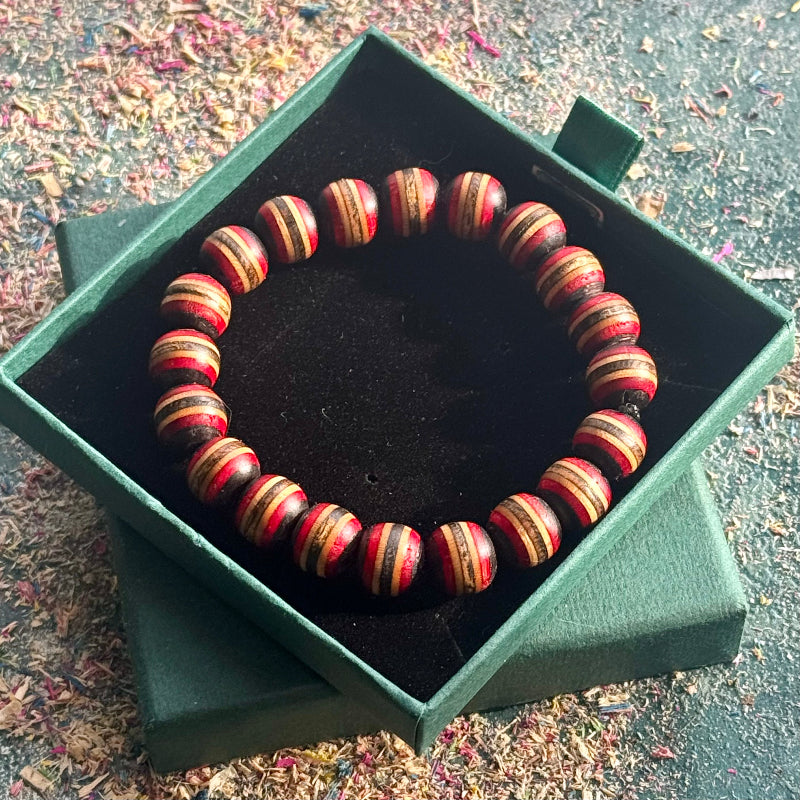 Handmade bracelet with red and black recycled skateboard wood beads displayed in an open green gift box.