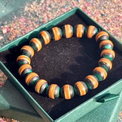 Handmade skateboard wood bracelet with green and natural colour tones, shown in a gift box on a textured surface.