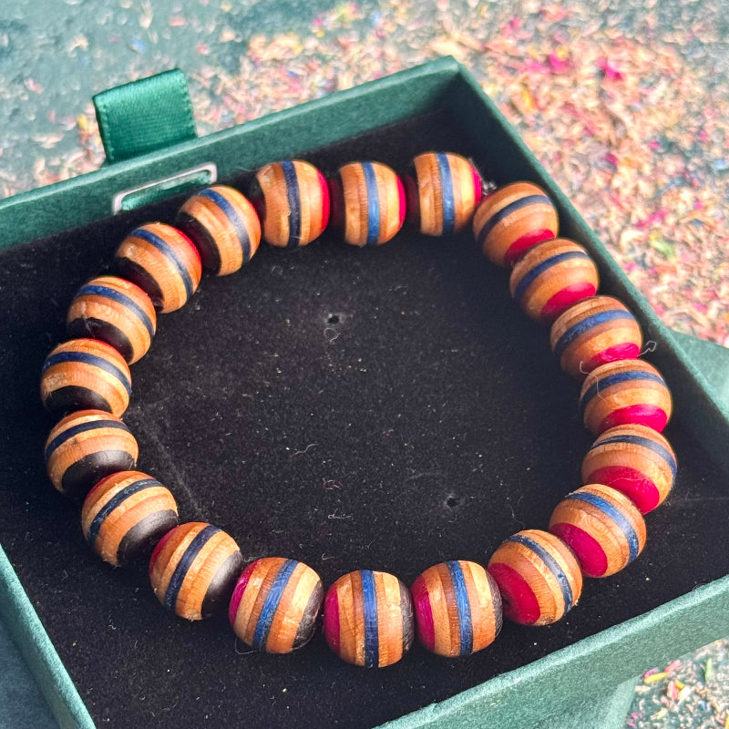 A black, pink and grey bracelet made from recycled skateboard wood with oiled wooden finish, handmade by Baltic Dew