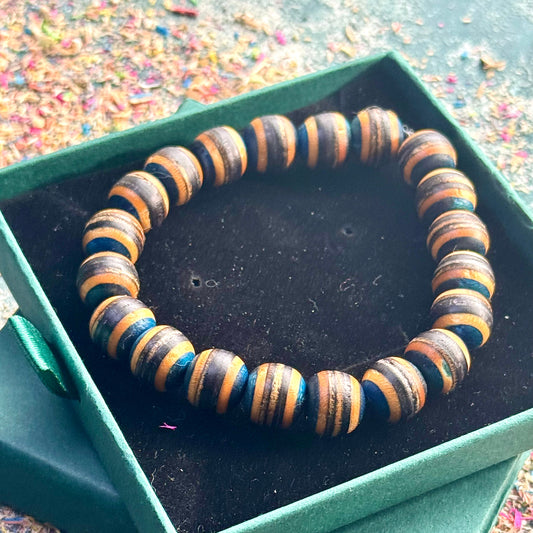 Handmade bracelet crafted from recycled skateboard wood with blue and black colour tones, shown in a green gift box.