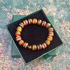 Recycled skateboard bracelet with Baltic amber bead displayed in an open green jewellery box.