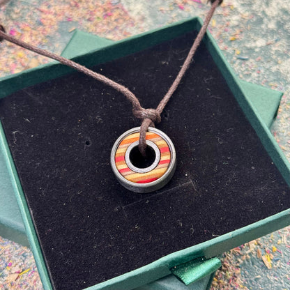 Red Orange Ball Bearing Skateboard Pendant made of layered wood and metal bearing on brown cord in green box with black velvet lining