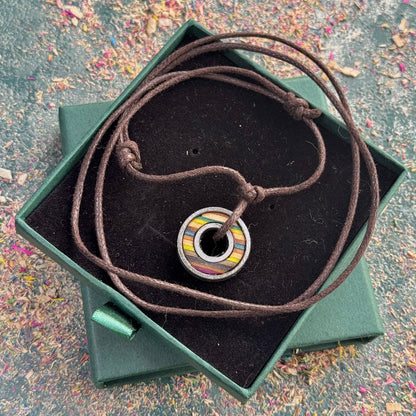 Recycled skateboard bearing pendant with moss green and blue colour tones on a brown cord, displayed in a gift box.