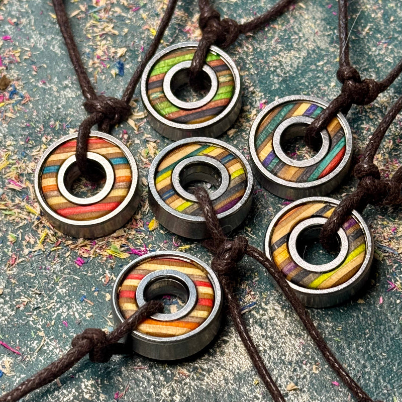 Assorted skateboard bearing pendant necklaces made from steel bearings and recycled skateboard maple in layered colours.