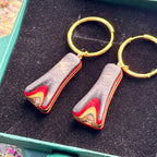 Handmade wooden hoop earrings showing red, black and natural skateboard colour layers.