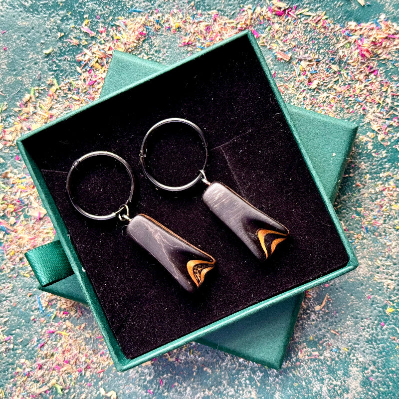 Dark black recycled skateboard hoop earrings displayed on black stainless steel hoops.