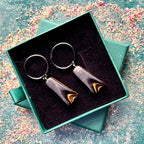 Dark black recycled skateboard hoop earrings displayed on black stainless steel hoops.