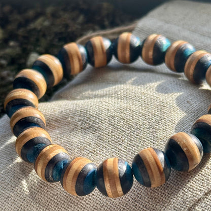 A black and grey bracelet made from recycled skateboard wood with oiled wooden finish, handmade by Baltic Dew