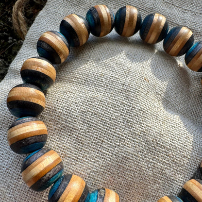 A grey and pink bracelet made from recycled skateboard wood with oiled wooden finish, handmade by Baltic Dew