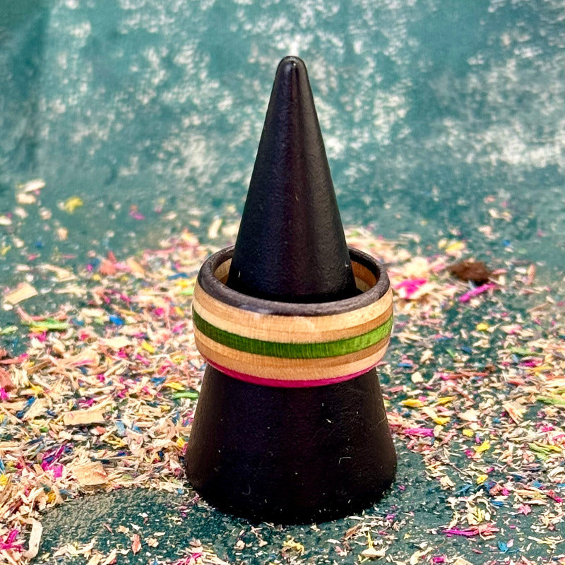 Pink, green and black skateboard maple ring on a black holder, showing the full band.