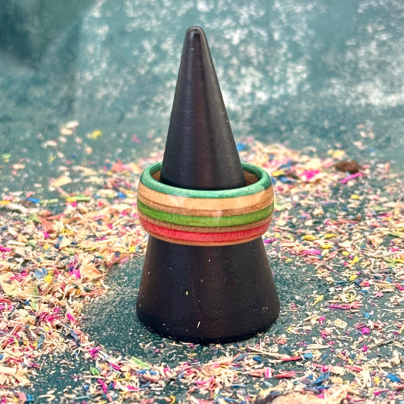 Orange, red and green skateboard maple ring on a black holder, seen from the side.